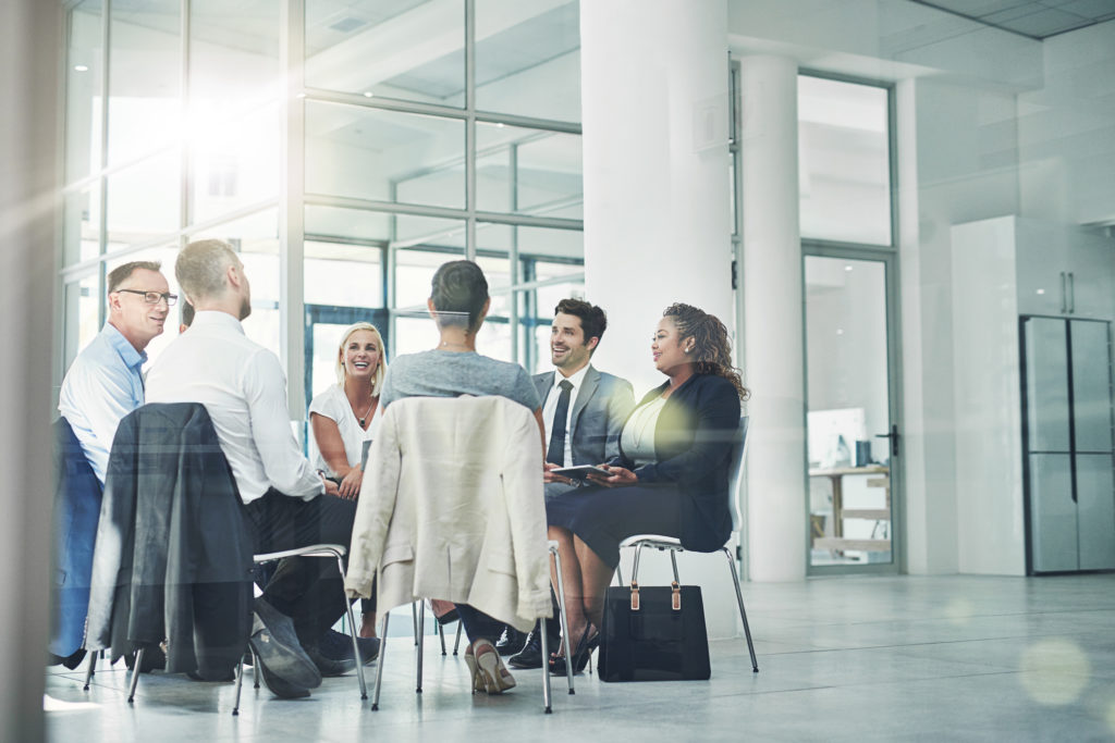 Shot of a group of coworkers talking together while sitting in a circle in an office